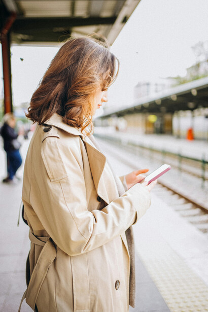 At a quiet train station platform, a woman stands waiting patiently