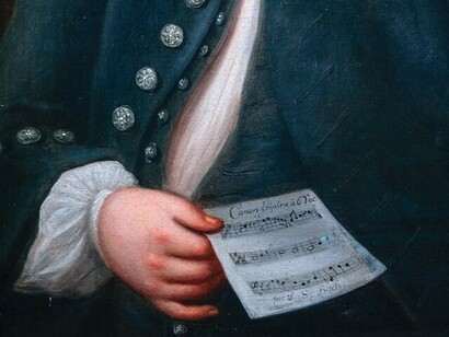 La mano de Bach sosteniendo una partitura nos recuerda el poder que tiene la obra de forma independiente y lo que tiene que enseñarle a quienes la difrutan