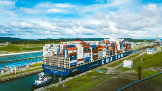 A vast cargo ship passing through the Panama Canal, representing the strategic importance of maritime trade and regional waterways
