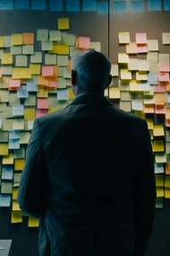 A man staring at a board filled with colorful adhesive notes after a brainstorming session