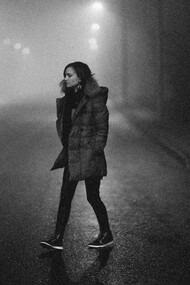 A woman walking through a dimly lit street at night