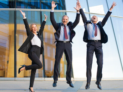 Joyful business team celebrating their achievements together outside a sleek glass office building