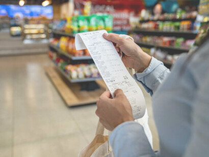 In the face of rising living costs, a woman reviews her receipt at a convenience store — a glimpse into the daily struggles of families across the USA