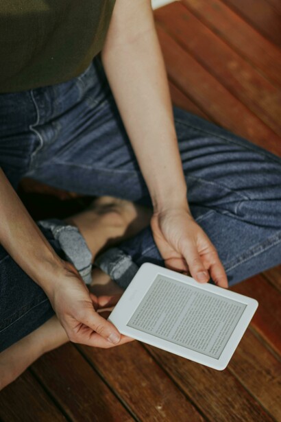 Mulher lê livro em leitor de e-books. Chegamos ao século XXI, onde a leitura enfrentou talvez seu maior desafio até agora: a revolução digital. Os e-books, audiolivros e plataformas de leitura online transformaram a forma como consumimos textos. Hoje, você pode carregar uma biblioteca inteira no seu bolso, algo inimaginável há cem anos

