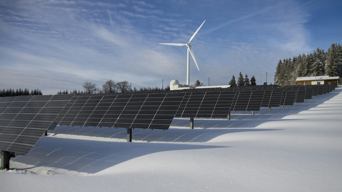 Solarpark und eine Windmühle in einer Winterlandschaft