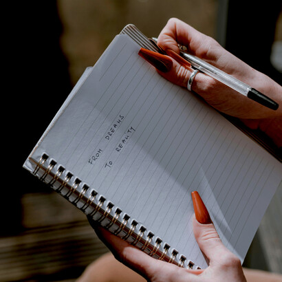A woman in a brown blazer holds a cup of coffee, lost in quiet thought