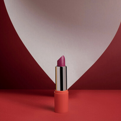 A luxurious lipstick displayed against a vibrant red background