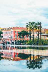 The allure of Nice, France, as people stroll along the streets near elegant buildings, immersing themselves in the picturesque ambiance of this enchanting destination on the French Riviera