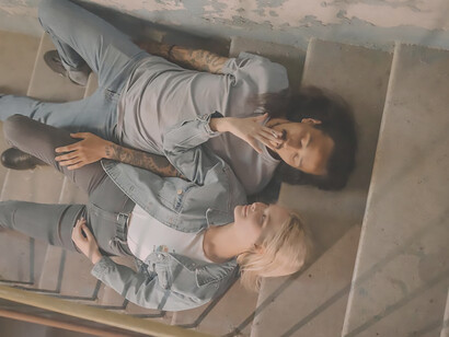 A woman and a man, both clad in blue denim jeans, sit on the stairs, defiantly smoking despite the imposition of high tobacco taxes