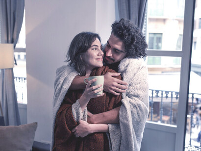 La chaleur du foyer dans sa forme la plus simple: un couple rit et se serre dans des couvertures avec des tasses de café, montrant la beauté de la compagnie et de la chaleur du moment
