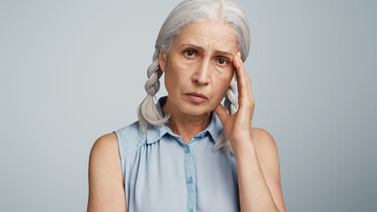 A senior woman with pigtails, dressed in a blue blouse, representing the experience of living with Alzheimer
