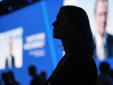 A woman’s silhouette in a dimly lit conference room, listening closely
