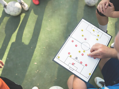 Coach demonstrating football tactics to players during practice