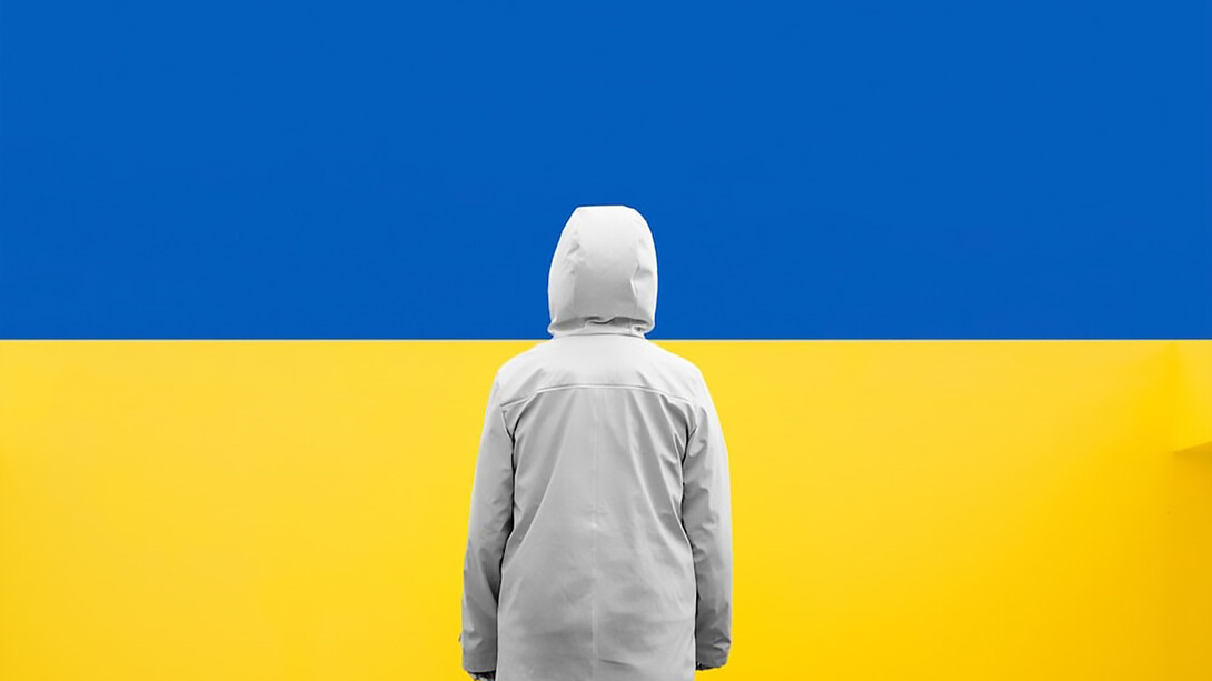 A child standing in front of a blue and yellow wall, Ukrainian flag colors