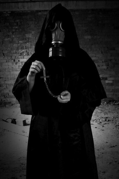 Angel of death holding a religious symbol upside down wearing a gas mask