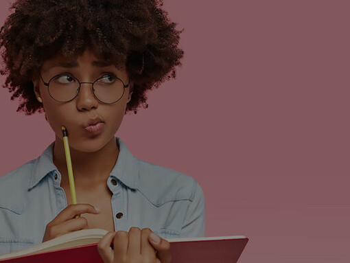 Captured in an indoor setting, a radiant female student holds a pencil with delight, her face illuminated by the joy of discovering a brilliant idea for her composition