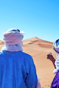 Two travellers gazing across the desert in M'hamid El Ghizlane, representing the quiet allure of the Sahara’s vast and timeless horizons