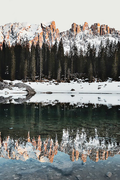 The majestic silhouette of mountains and the lush canopy of trees mirrored perfectly in the serene surface of a lake