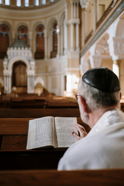 A man wearing a kippah prays quietly as he reads the Bible