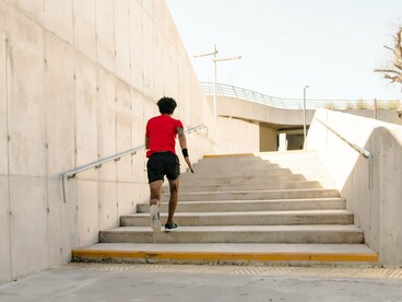A man sprinting up outdoor steps with determination, symbolizing the power of snack-size fitness to improve cardiovascular health