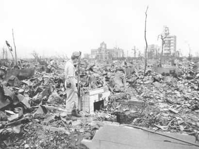 A man stands next to the remnants of a tiled fireplace after the atomic bomb destroyed Hiroshima, Japan in 1945