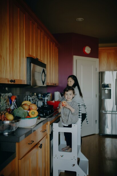 Menino come uma maçã enquanto mãe cozinha