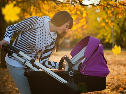 A woman smiles as she plays with the baby that is still in the stroller