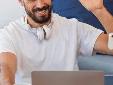 A social media influencer recording a vlog at home while working on a laptop