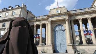 Mujer musulmana con nicab delante de la Asamblea Nacional de Francia, órgano legislativo que prohibió su uso en espacios públicos en 2010