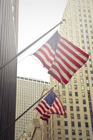 Bandiere americane che sventolano tra i grattacieli di una città finanziaria negli Stati Uniti