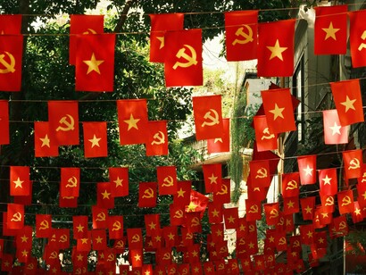 Faixas e bandeiras com referências ao comunismo ocupam o cenário de uma rua arborizada de uma cidade. O texto utiliza o tema para discutir valores, disputas ideológicas e a percepção do autor sobre o momento político contemporâneo