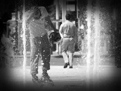 A construction worker cools off in a fountain after work during the heat wave