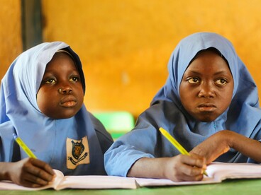 Two girls work on classroom assignments, representing the importance of sustained education in protecting children's future