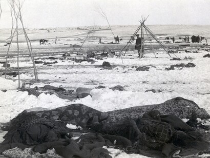 Il campo di Big Foot tre settimane dopo il massacro di Wounded Knee; in primo piano i corpi di quattro Lakota Sioux avvolti in coperte; soldati statunitensi tra i detriti sparsi del campo, 1890