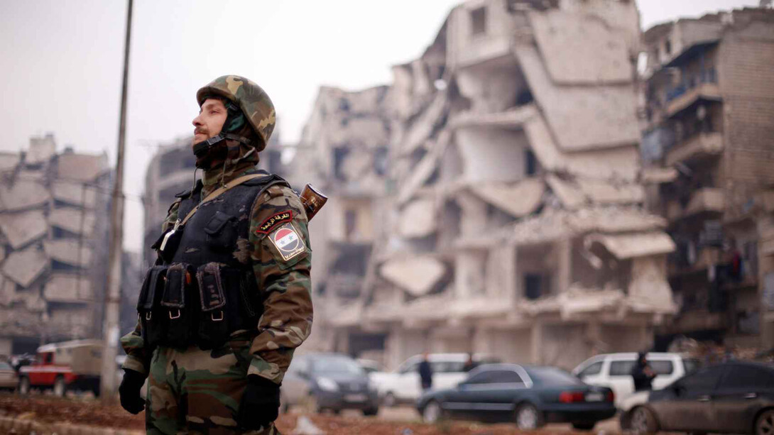 Un soldado de las fuerzas leales a Asad, cerca de edificios dañados en Alepo, Siria
