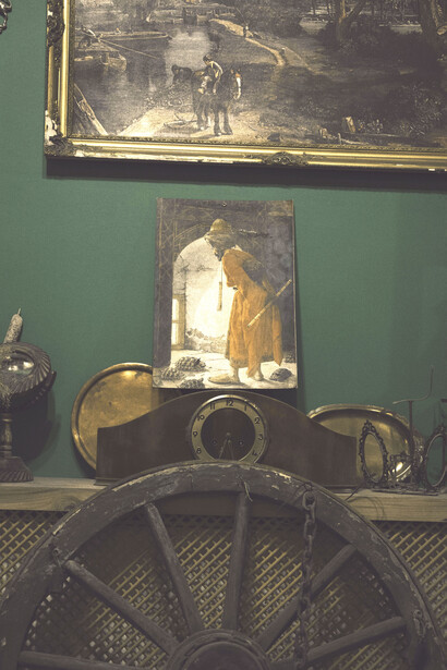 Cuadros y objetos colgados sobre un mueble, adornados por una rueda antigua
