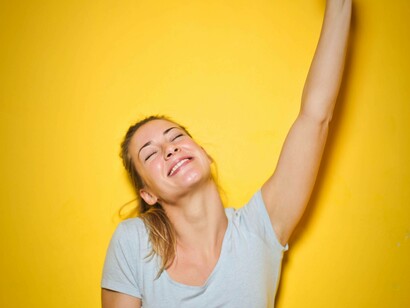 A woman with her eyes closed is smiling with a hand in the air to express her happiness