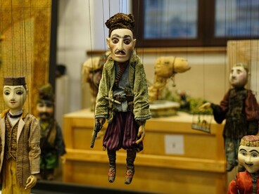 A collection of handcrafted string puppets suspended in display, representing the lasting artistry of traditional puppet making