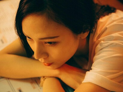 A woman who is an introvert has her arms crossed on a table as she rests her chin