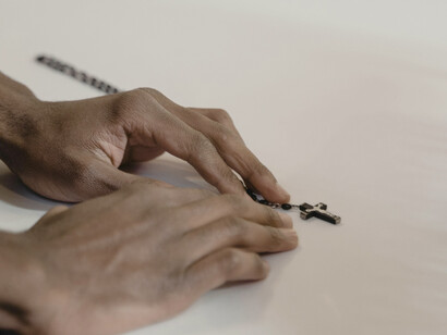 Unas manos sujetan y pequeño crucifijo. Busco entender por qué la maldad se arraiga en el corazón humano