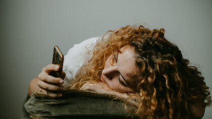 A woman in a gray sweater holding her smartphone