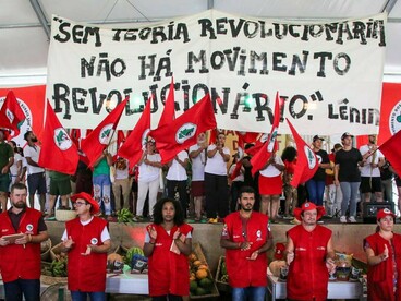 Militantes seguram bandeiras do MST e uma faixa com a frase "Sem teoria revolucionária não há movimento revolucionário. Lênin". O texto debate a necessidade de repensar estratégias e projetos políticos diante das transformações do mundo contemporâneo