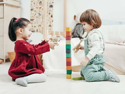 Duas crianças brincam juntas no chão, explorando blocos coloridos de montar e experimentando diferentes possibilidades de construção. Por meio dessas atividades lúdicas, a criança desenvolve a criatividade, a coordenação motora e o raciocínio, construindo conhecimentos a partir da interação com os objetos e com outras crianças