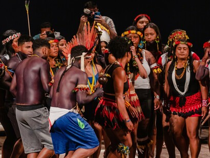 Evento: O Brasil Indígena - uma nova foto da população indígena, 2023. A produção coletiva também tem se mostrado uma peça-chave dessa cena. O MAHKU (Movimento dos Artistas Huni Kuin), documentado no livro "Huni Kuin: Yuxibu" (2020), transformou cantos xamânicos em pinturas de cores vibrantes que têm circulado em exposições nacionais e internacionais. Fundado pelo pajé Ibã Huni Kuin, o coletivo desenvolve trabalhos que traduzem visualmente experiências espirituais relacionadas à medicina tradicional ayahuasca, criando pontes entre mundos aparentemente distintos