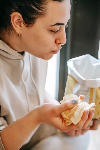 With her hands, the girl relishes a bag of potato chips