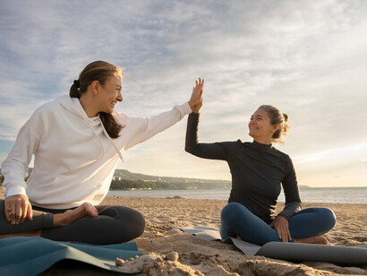 A mother and daughter unite in beachside yoga, reflecting the beauty of family bonding and holistic wellness against the backdrop of tranquil coastal scenery