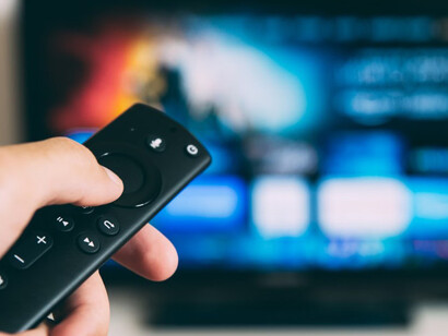 A person holding a black remote control, effortlessly browsing through streamlined platforms