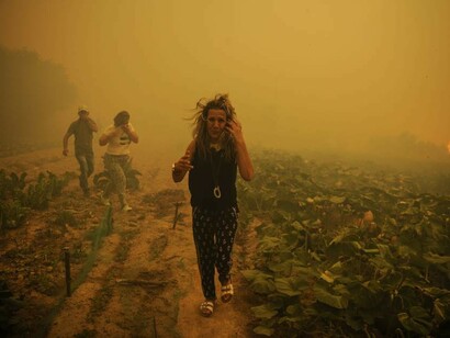 LA gente huye del fuego entre el humo