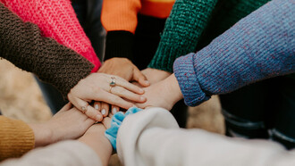Team joining hands to show solidarity for the collaborative spirit