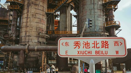 A city sign in China set against the backdrop of factories and trade hubs, reflecting the nation’s growing technology industry and global economic influence